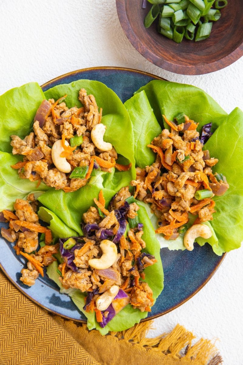 blue plate of Thai ground turkey lettuce wraps with golden napkin to the side.