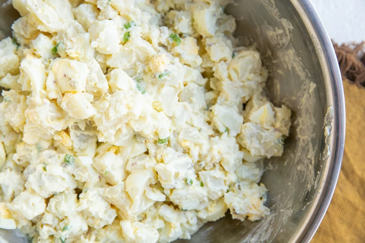 Finished creamy potato salad in a mixing bowl.