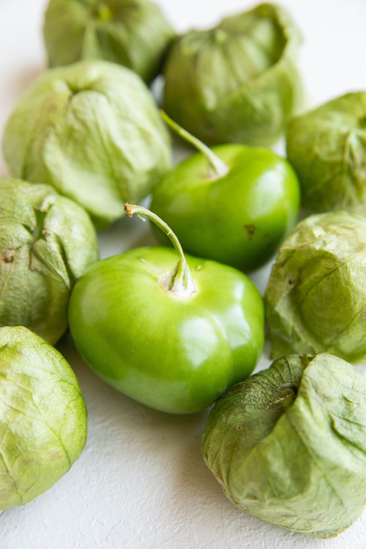 Tomatillos sitting on a white backdrop