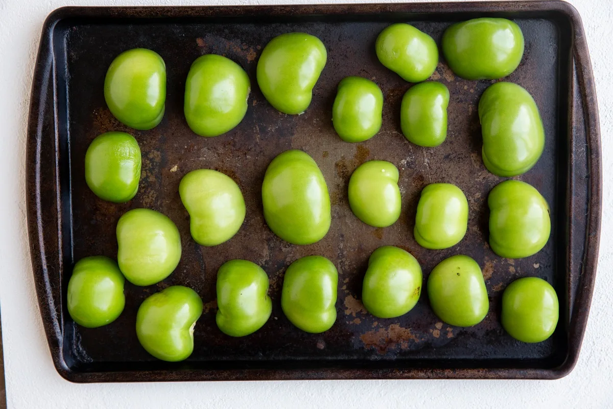 Tomatillos cut in half on a baking sheet, ready to go into the oven.