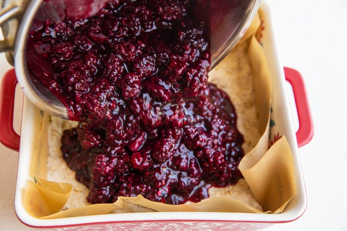 Pouring blackberry jam filling over the baked crust