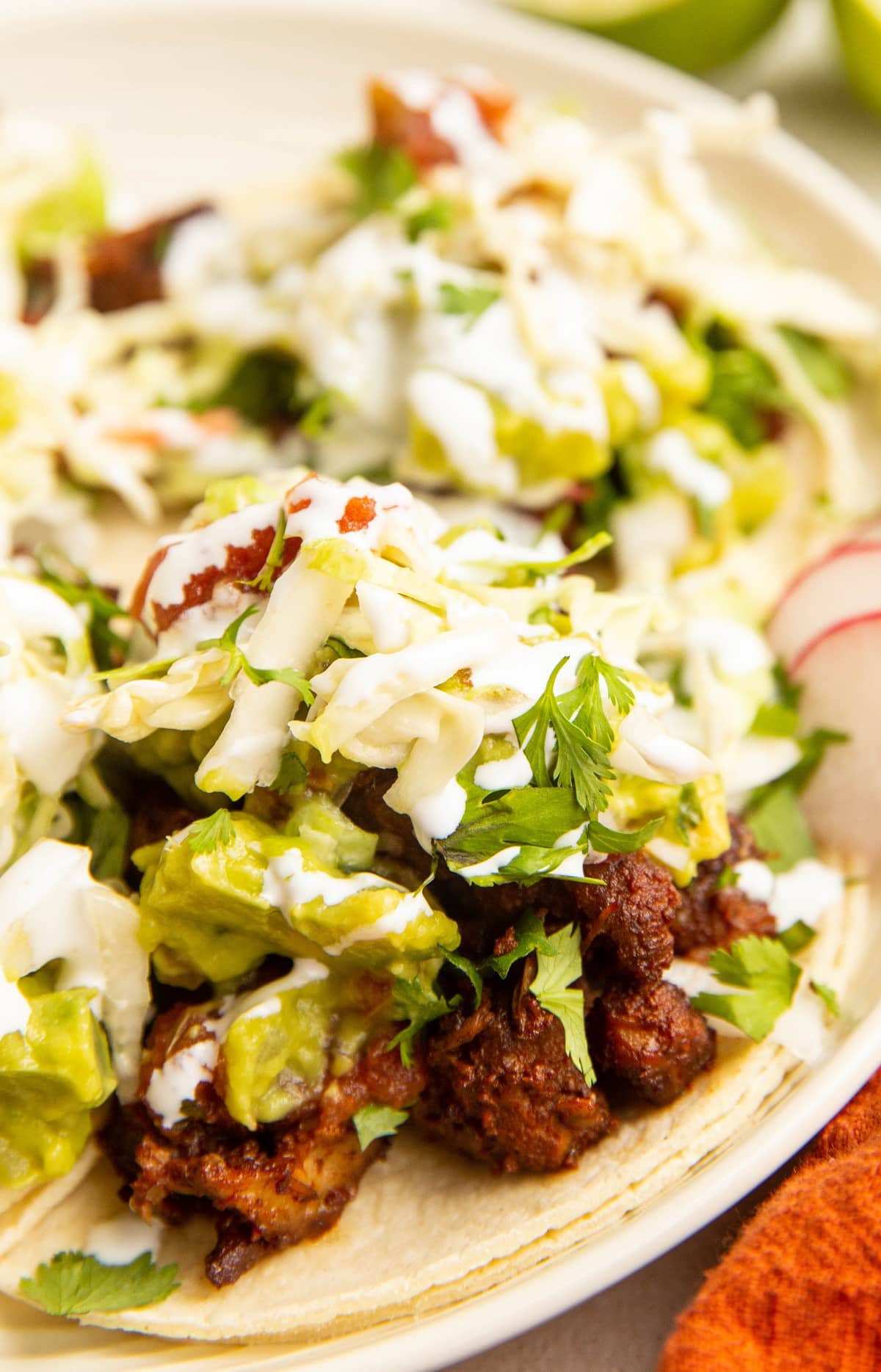 close up image of al pastor tacos on a plate with toppings