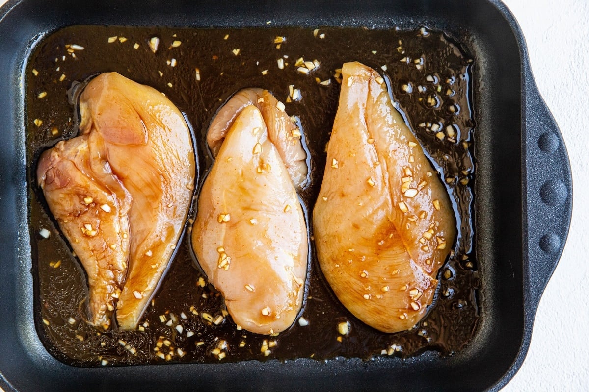 Raw chicken and marinade in a casserole dish