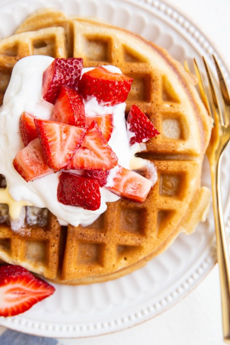 close up top down photo of waffles with strawberries and whipped cream