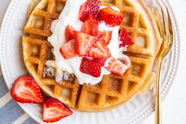 horizontal photo of amazing fluffy waffles with fresh strawberries and cream