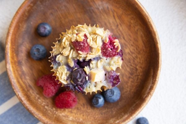 horizontal photo of baked oatmeal muffin on a plate with fresh berries