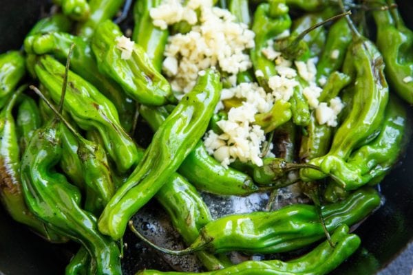 skillet with cooked shishito peppers and butter and garlic