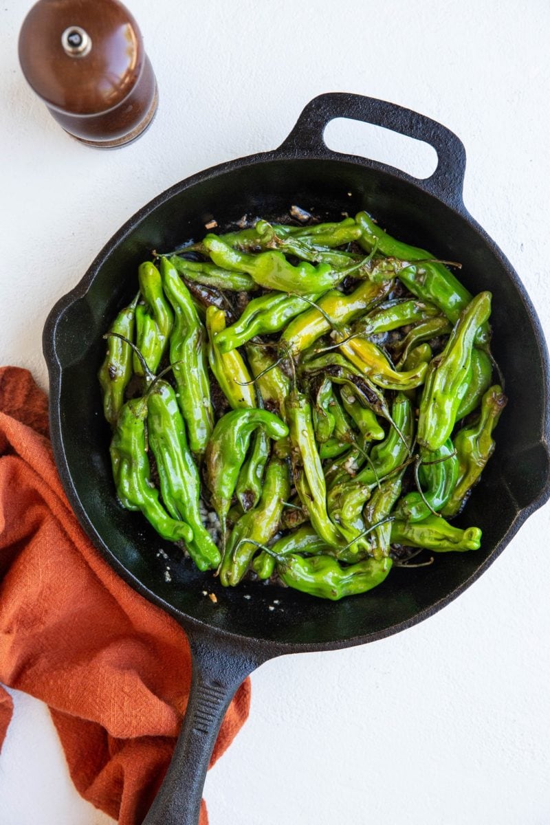 cast iron skillet with blistered shishito peppers