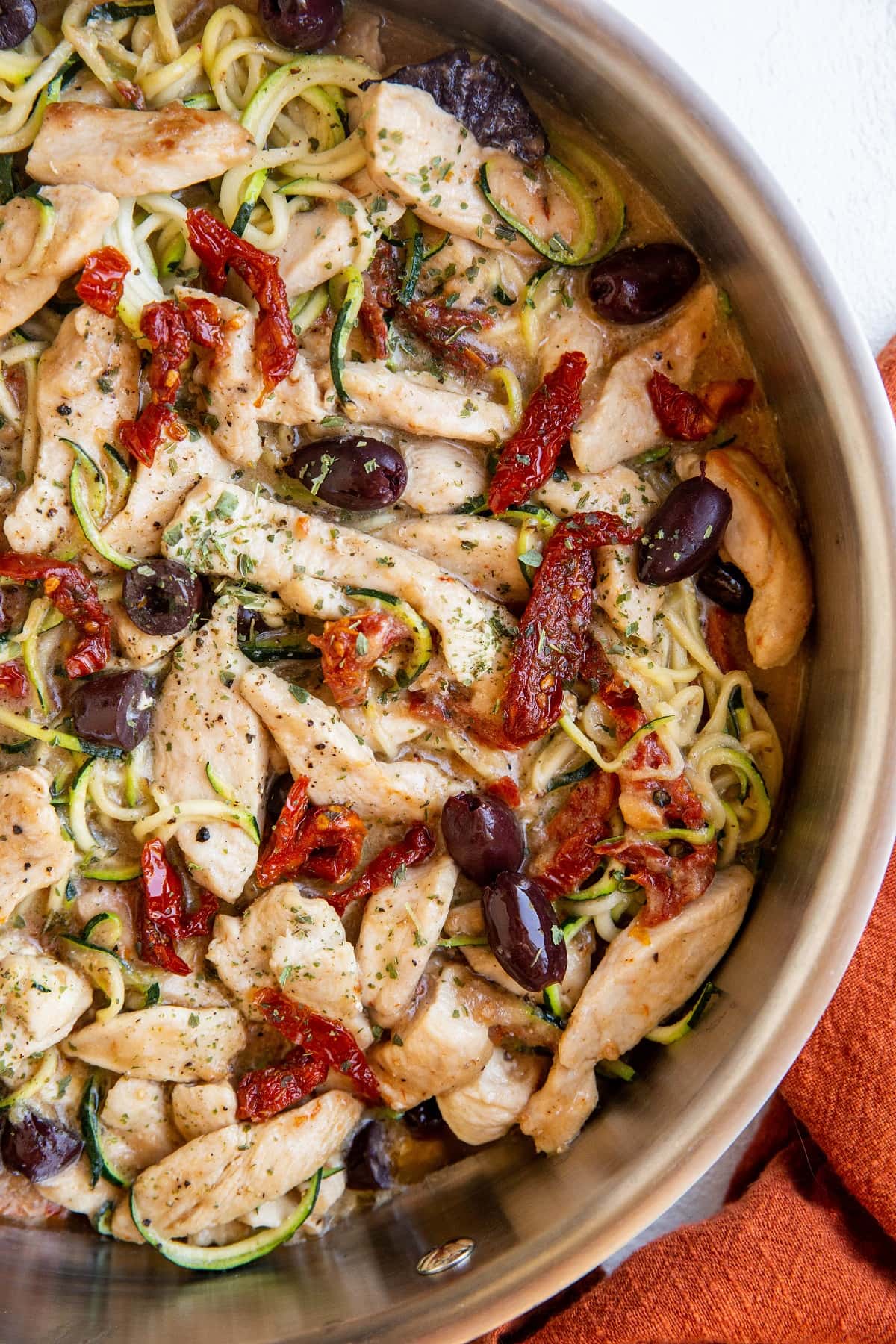 top down stainless steel skillet of zoodles and chicken