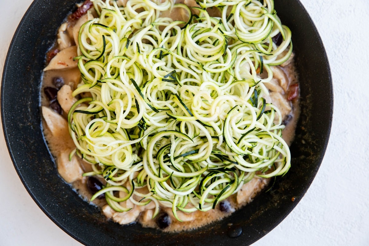Zucchini noodles in a skillet ready to be mixed in.