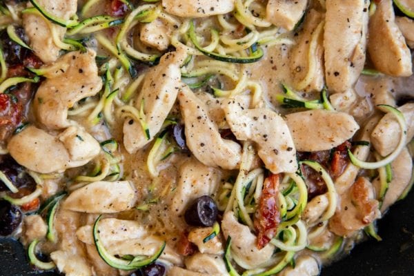 skillet with zucchini noodles, creamy chicken and sun-dried tomatoes