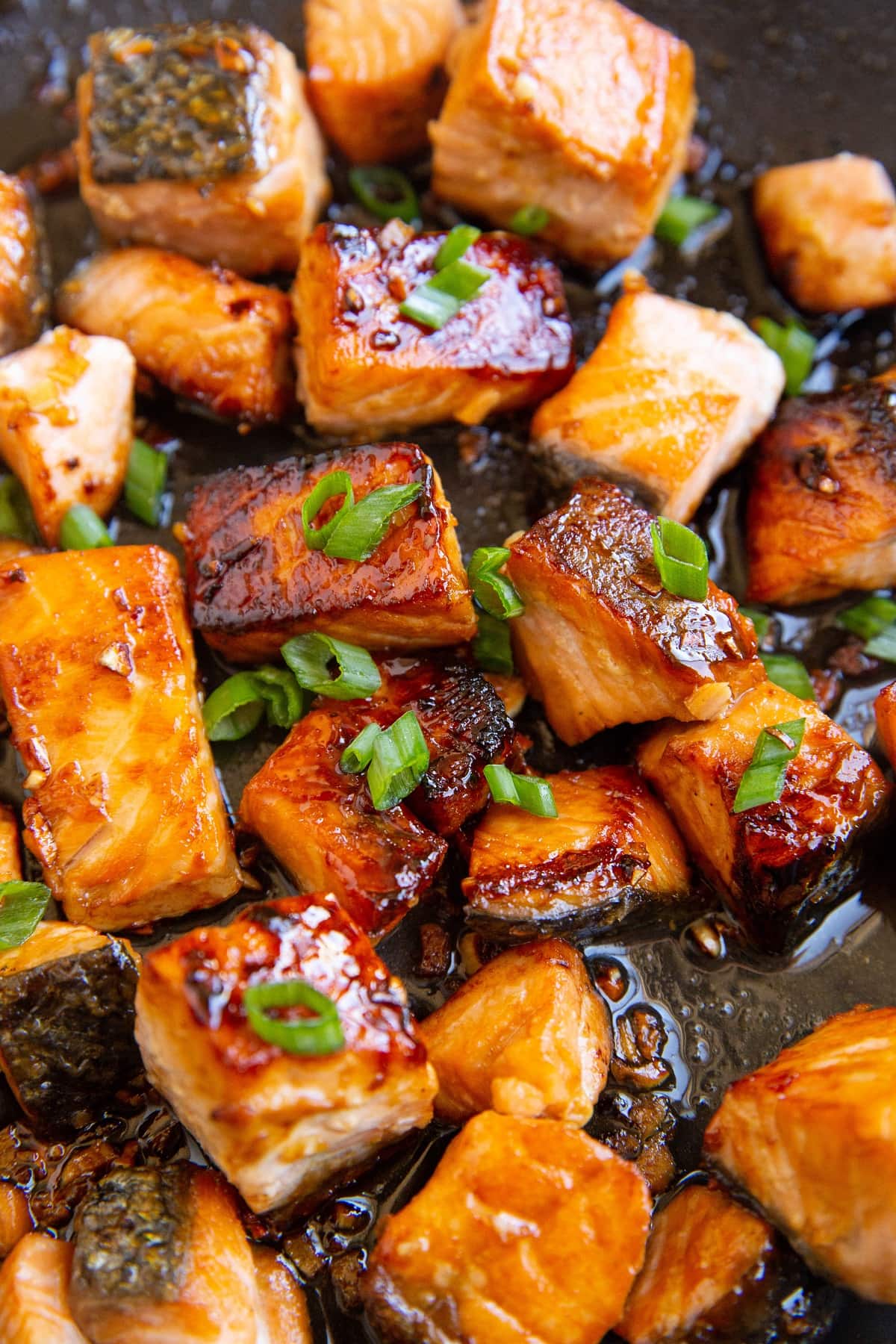 Close up shot of Asian Sesame Salmon in a skillet with green onion on top