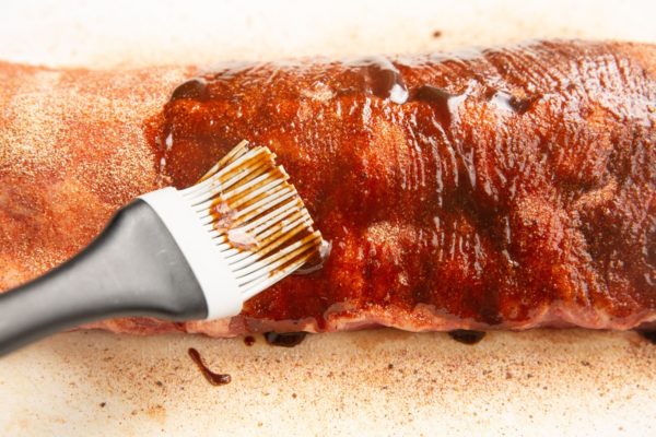 brushing bbq sauce over the ribs