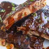 Stack of crock pot ribs on a white serving plate