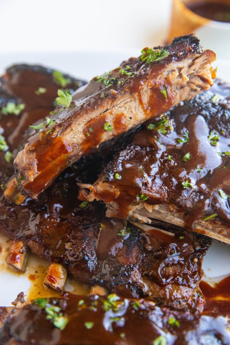 Stack of crock pot ribs on a white serving plate