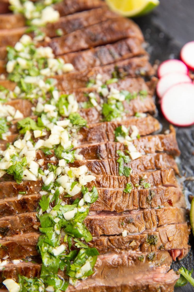 Sliced carne asada on a black slate