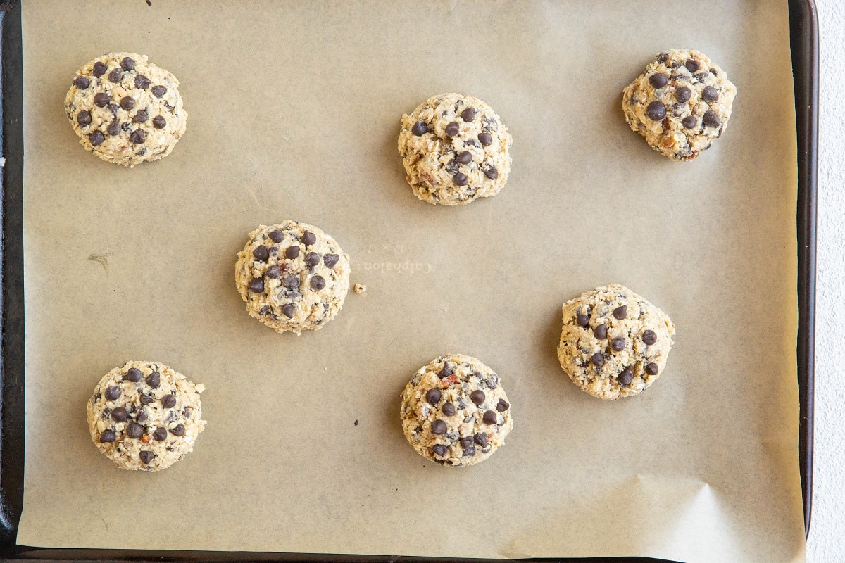 Large lumps of cookie dough on a parchment-lined baking sheet