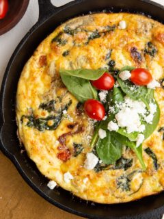 Cast iron skillet with Greek frittata and a golden napkin to the side