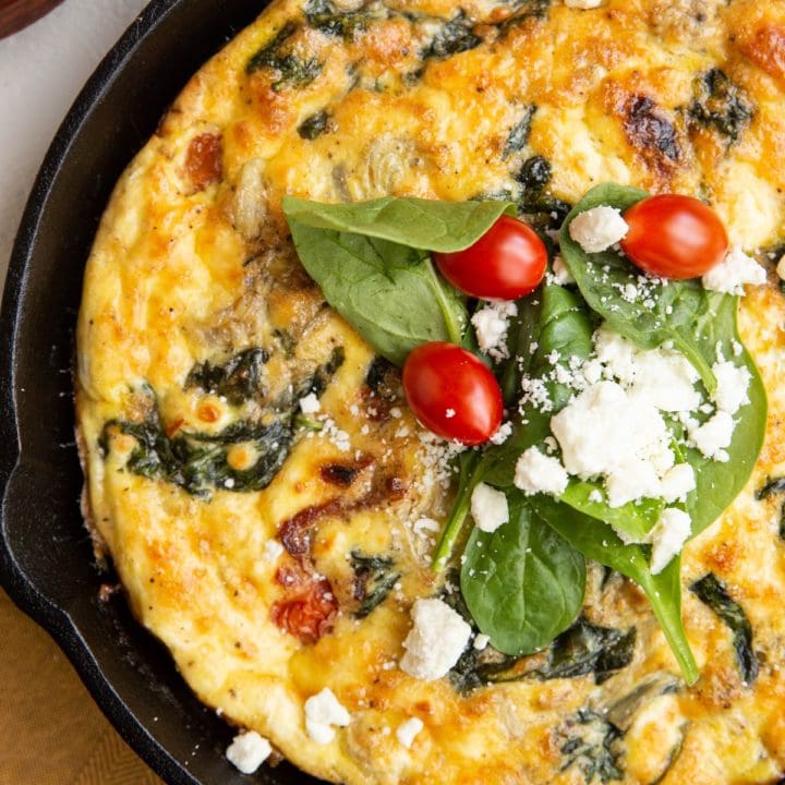 Cast iron skillet with Greek frittata and a golden napkin to the side