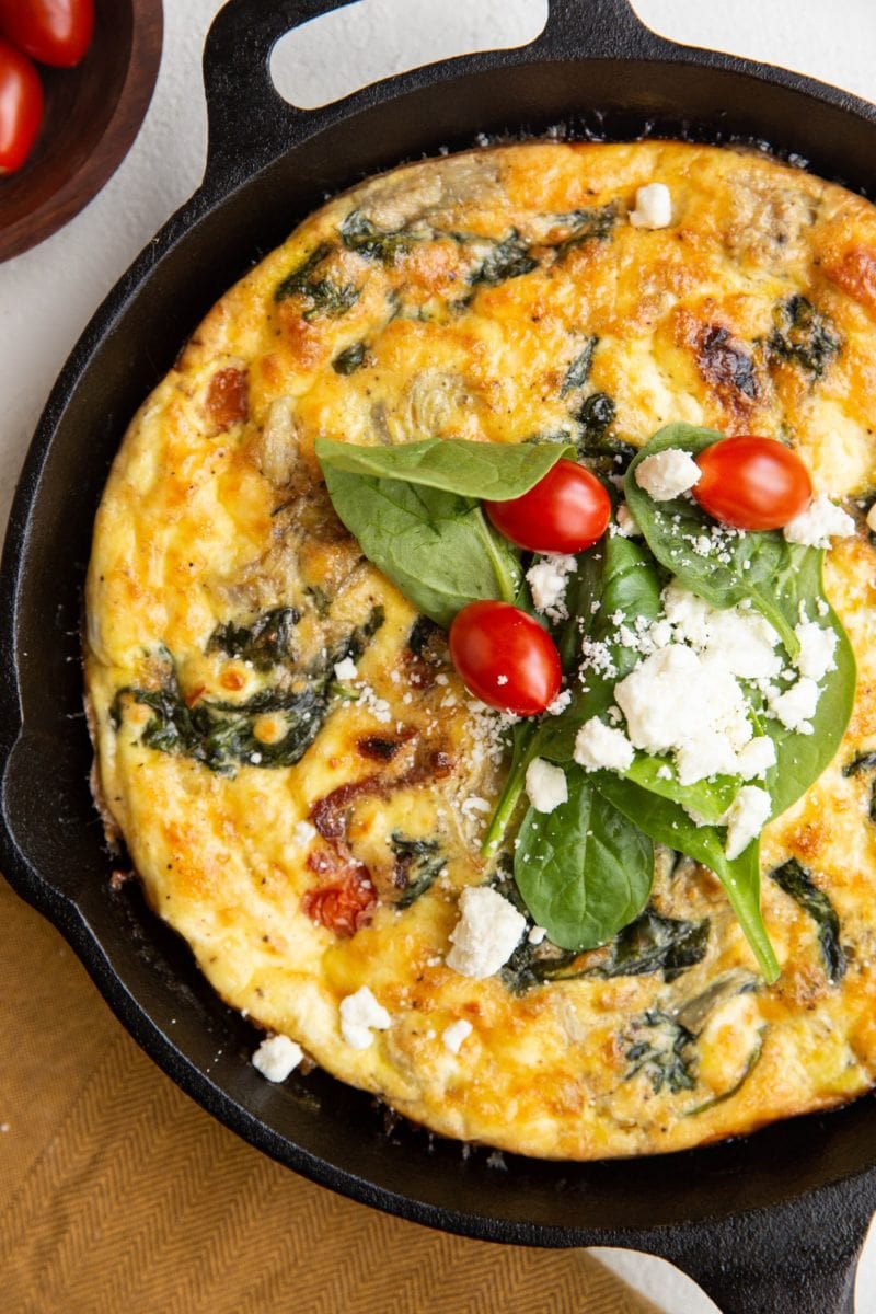 Cast iron skillet with Greek frittata and a golden napkin to the side
