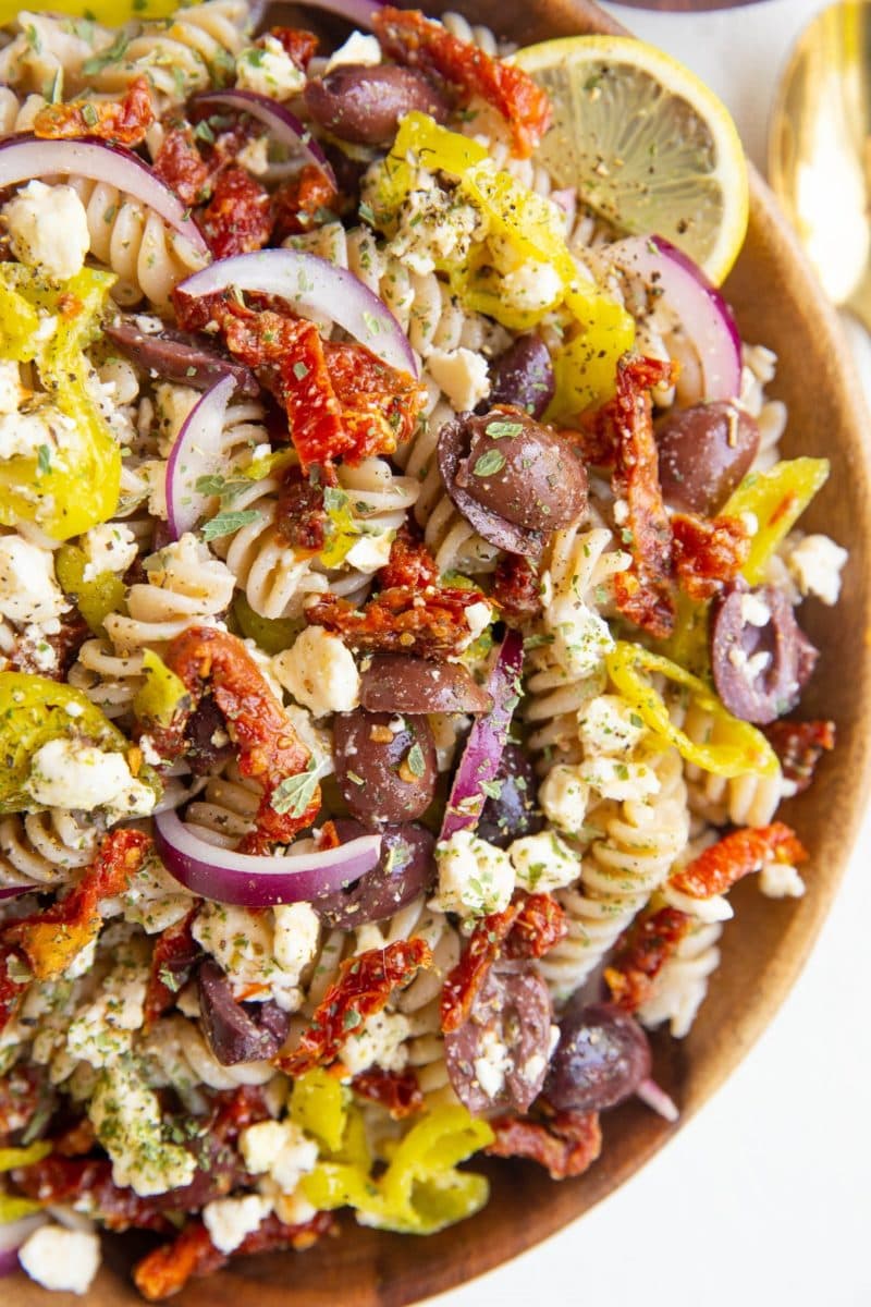 close up top down photo of Greek pasta salad in a wood bowl