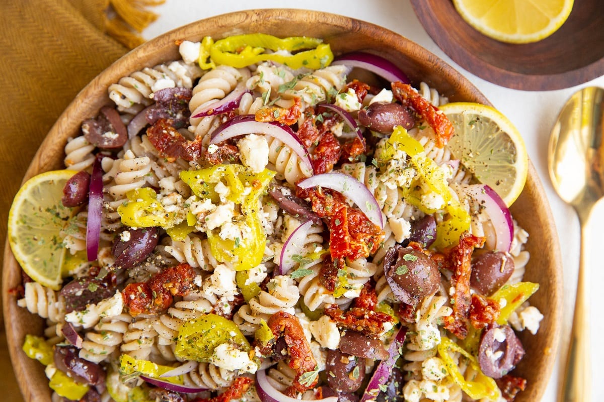 horizontal photo of Greek Pasta Salad in a wood bowl