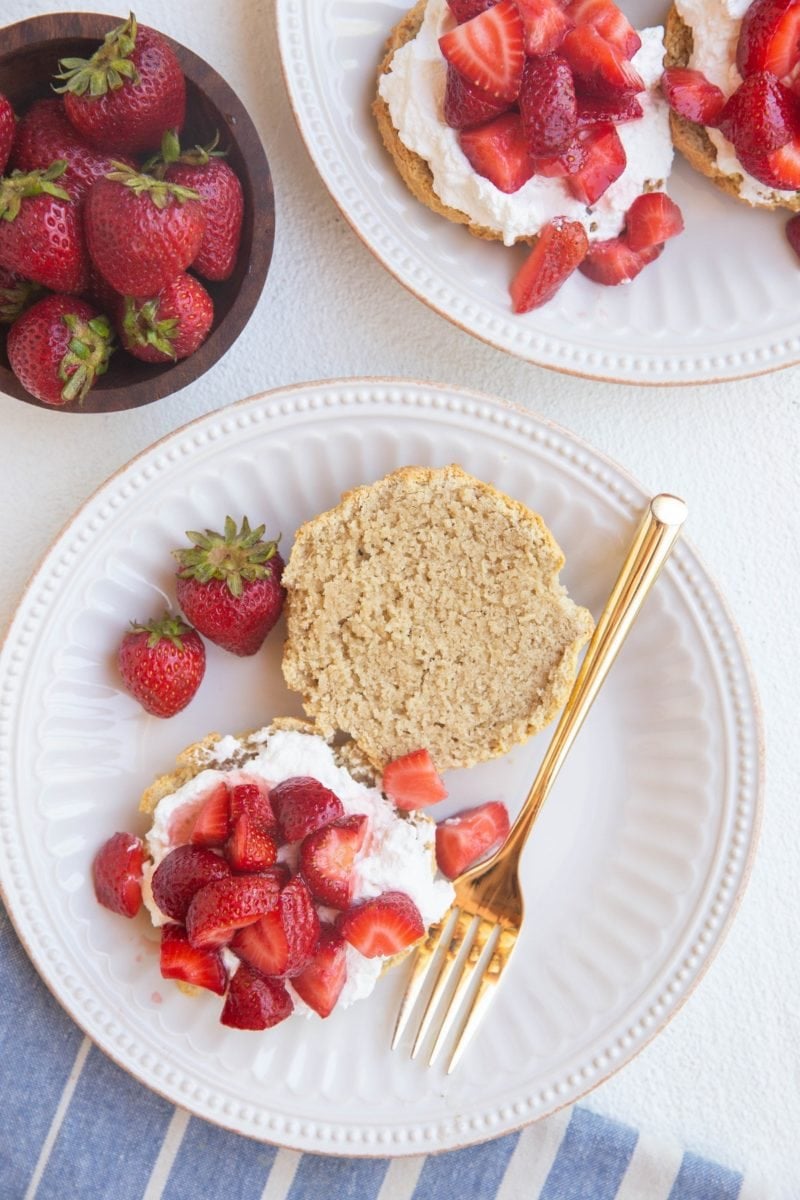 top down photo of strawberry shortcakes on two white plates with a blue striped napkin