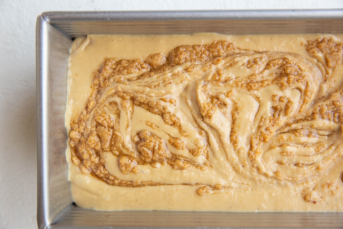 chickpea ice cream base in a loaf pan with peanut butter swirled in