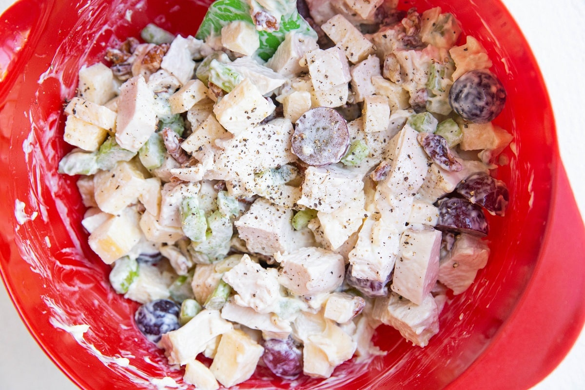 Ingredients for chicken salad in a red mixing bowl