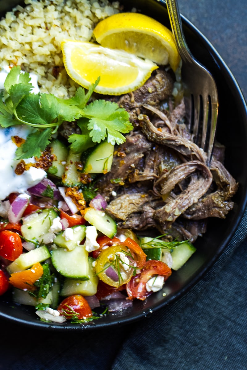 Greek shredded meat in a bowl with salad and lime