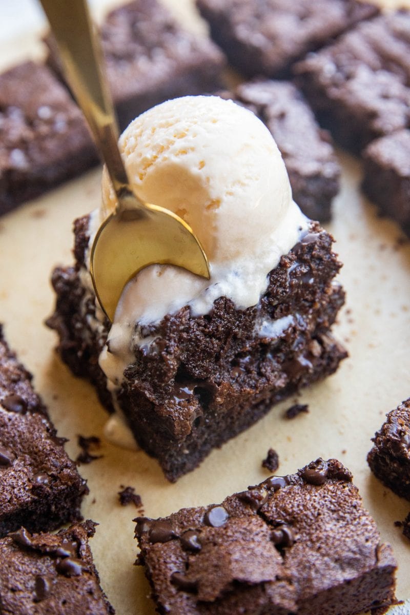 spoon digging into a stack of brownies with ice cream on top