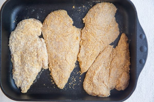 raw chicken breasts breaded in a casserole dish
