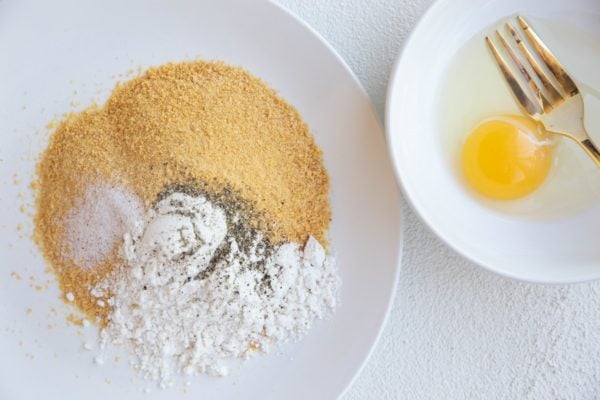bowl with an egg and plate with bread crumbs and flour