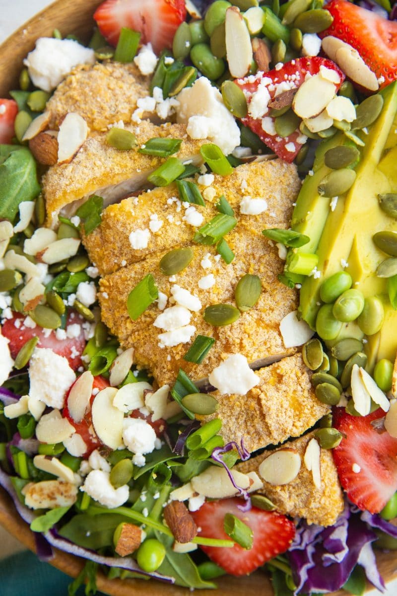 close up top down photo of baked crispy chicken salad with strawberries and avocado