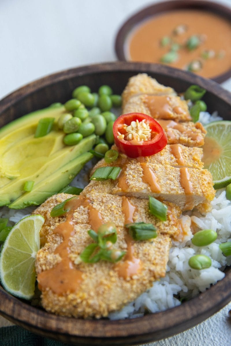 close up bowl of chicken katsu with rice, avocado and green onion
