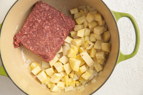 Ground beef in a pot with potatoes and onion