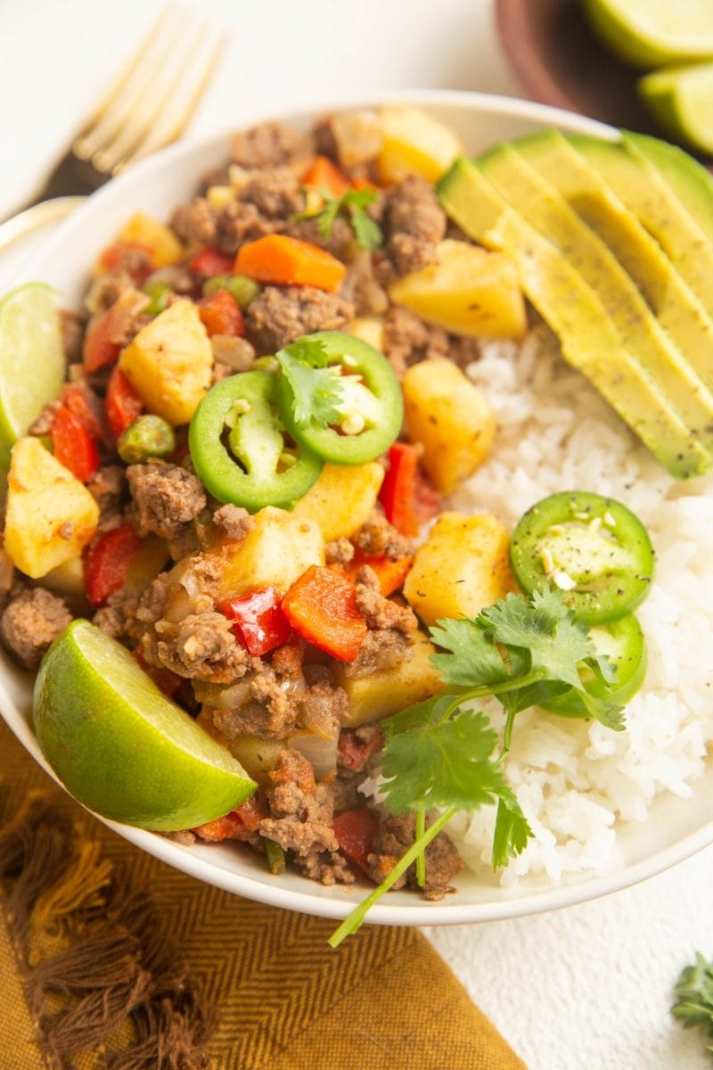 bowl of picadillo and rice with avocado and cilantro