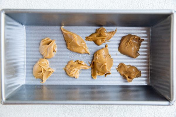 Lumps of peanut butter at the bottom of a loaf pan to make peanut butter ice cream