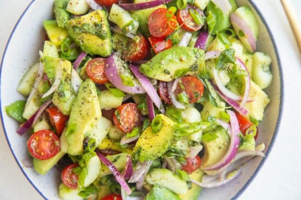 Horizontal photo of avocado salad in a bowl with a blue rim.