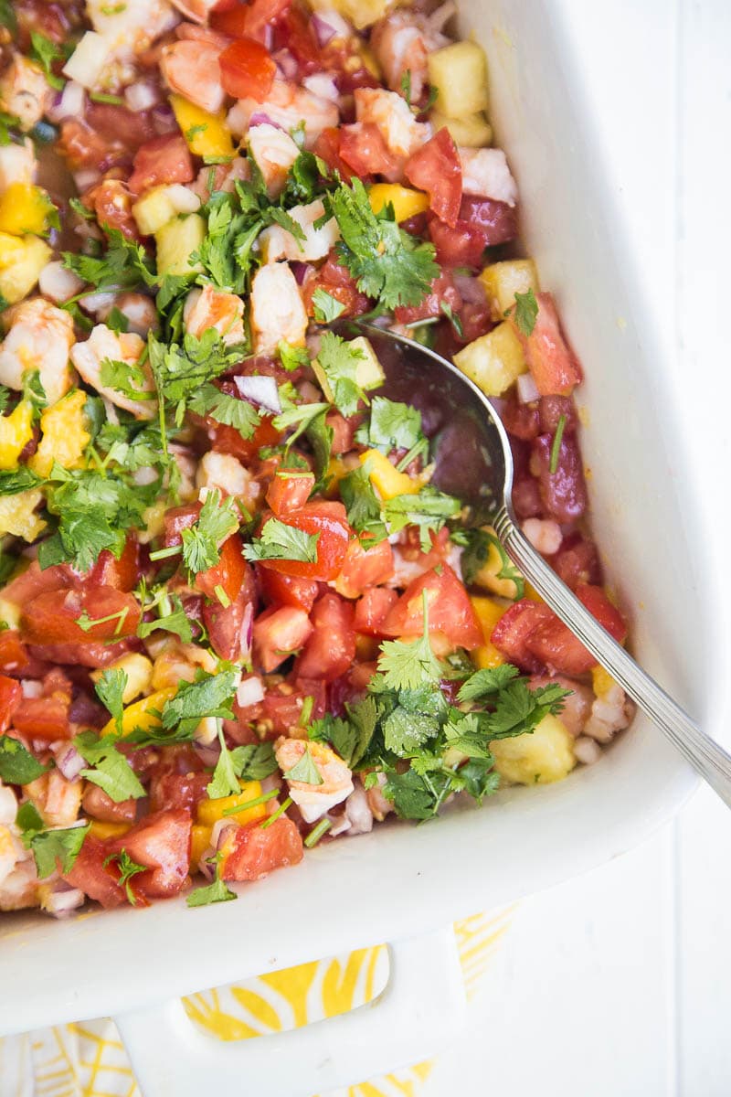 Casserole dish with tropical shrimp ceviche and a spoon