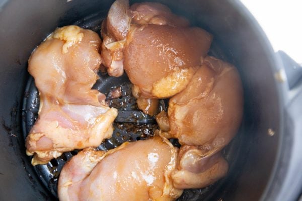 Raw chicken just added to an air fryer.