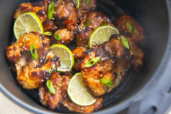 Finished asian chicken in the basket of an air fryer.