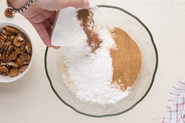 Pouring dry ingredients into a bowl to make coffee cake.