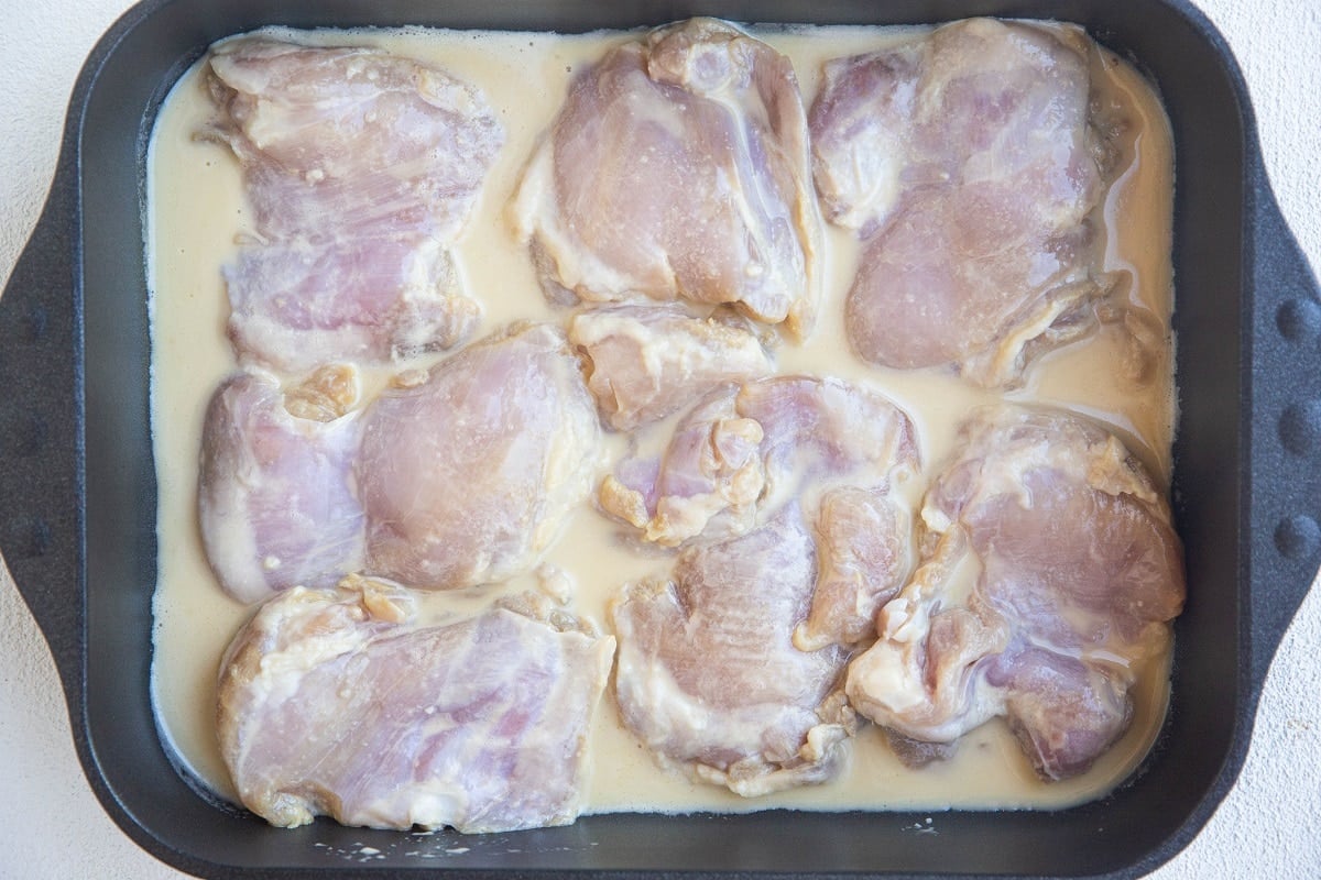 Chicken with marinade in a casserole dish, ready to go into the oven.