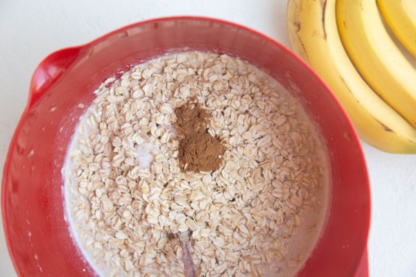 Mixing bowl with wet ingredients and dry ingredients on top for oatmeal.