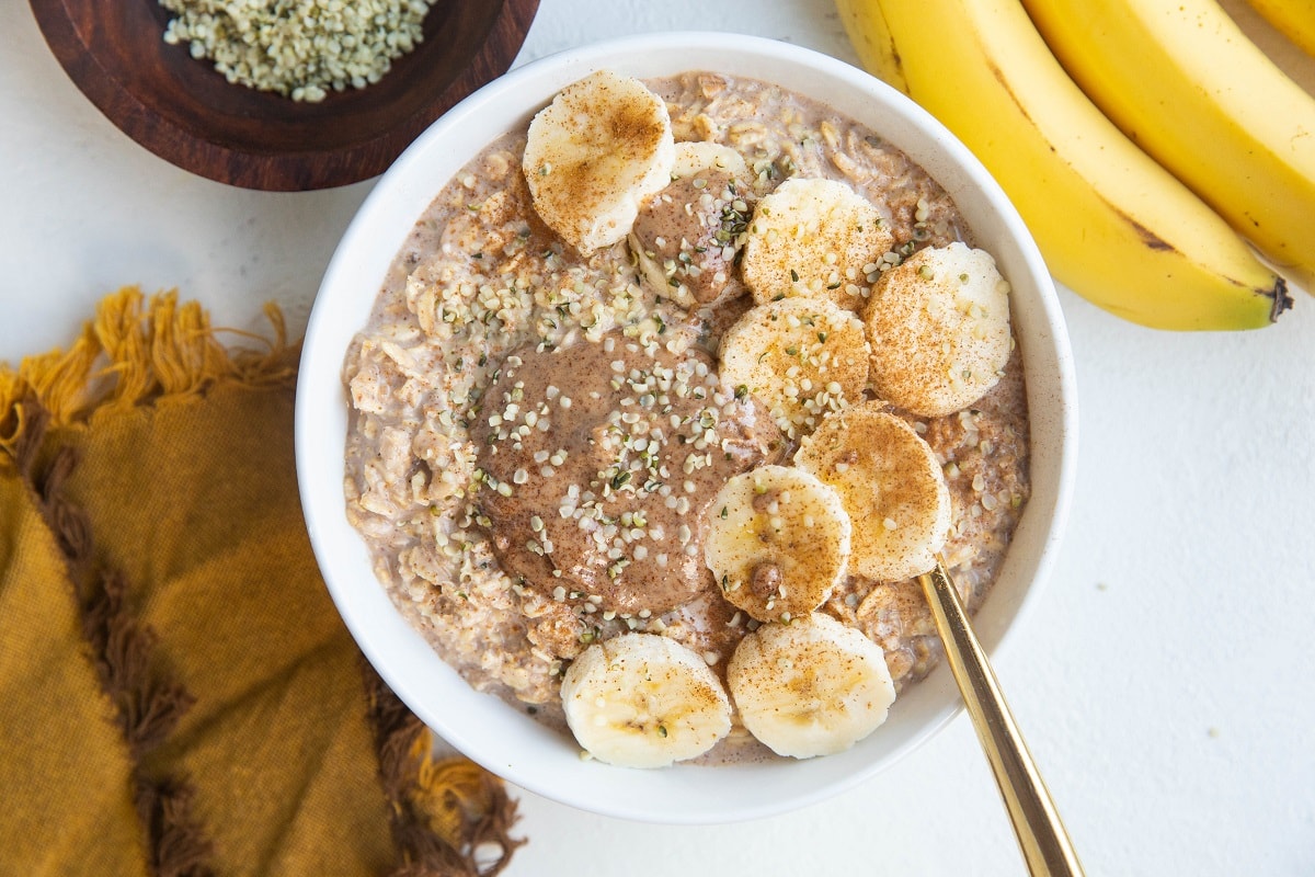 Horizontal image of bowl of oatmeal with bananas on top and almond butter.