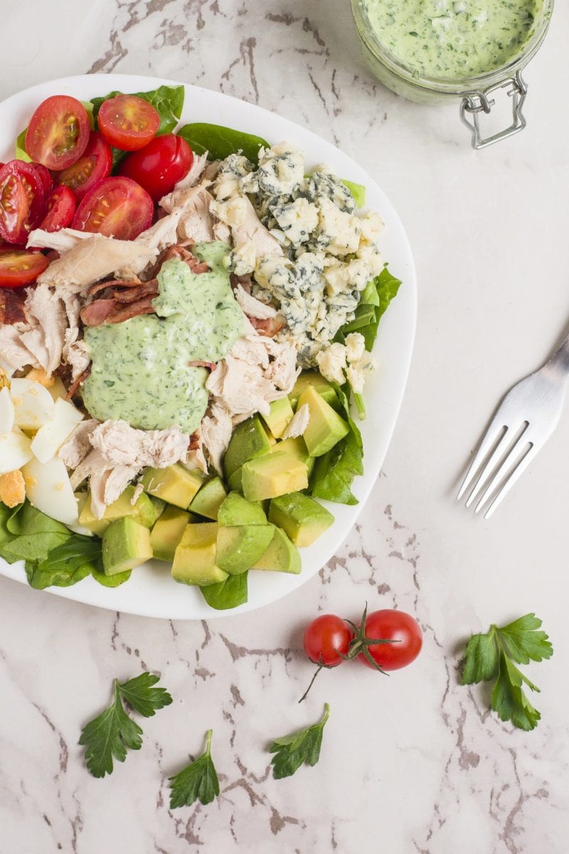 Cobb Salad on a white surface with dressing on top.
