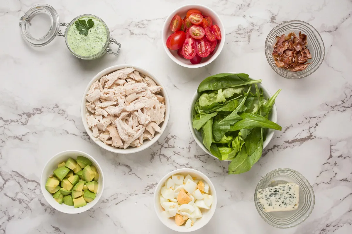 Ingredients for Cobb Salad laid out on a marble surface.