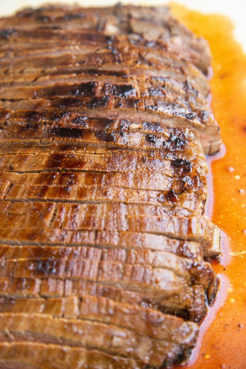 Cutting board with sliced flank steak, fresh off the grill.