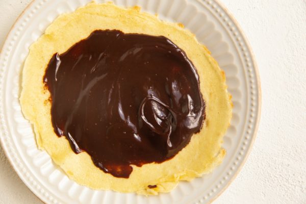 Chocolate spread on a crepe on a plate.